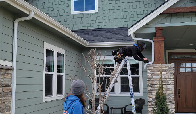 Two person working on installing downspout.