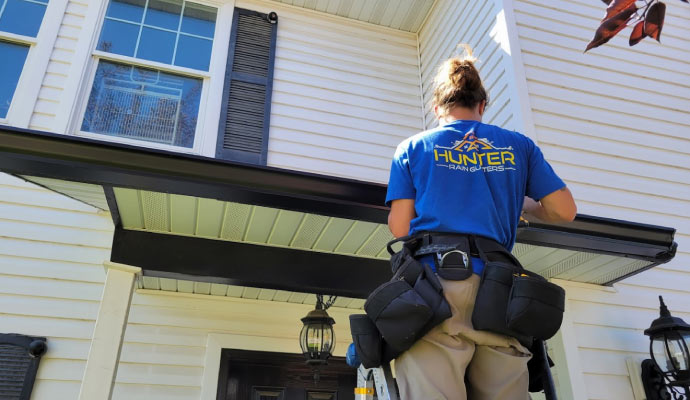 A person inspecting a roof gutter