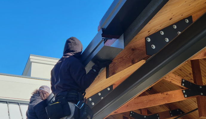 Person replacing roof gutter using equipment