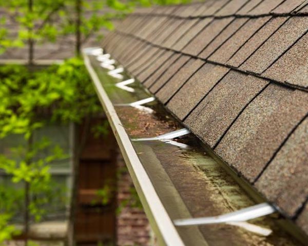A house's roof watter overflowing on gutter in the roof.