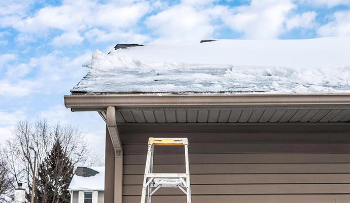 Snow and ice buildup along a roof edge and gutter, showing how blocked gutters can lead to winter roof damage.