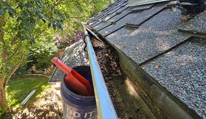 A roof gutter being cleared of leaves and debris to restore proper water flow and prevent overflow