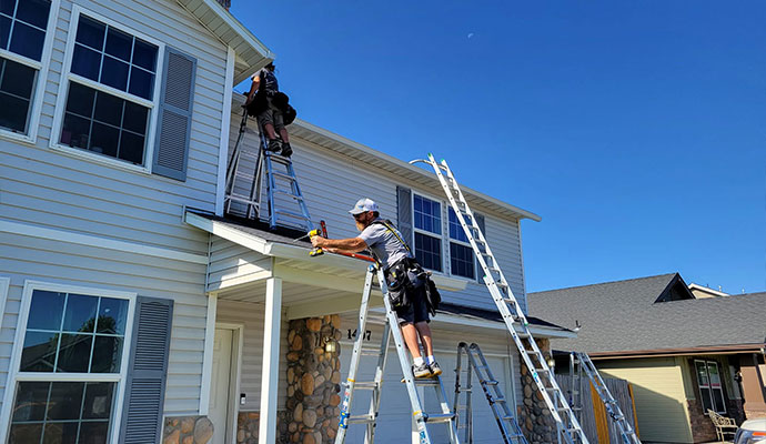 Technicians installing rain gutters on a residential home