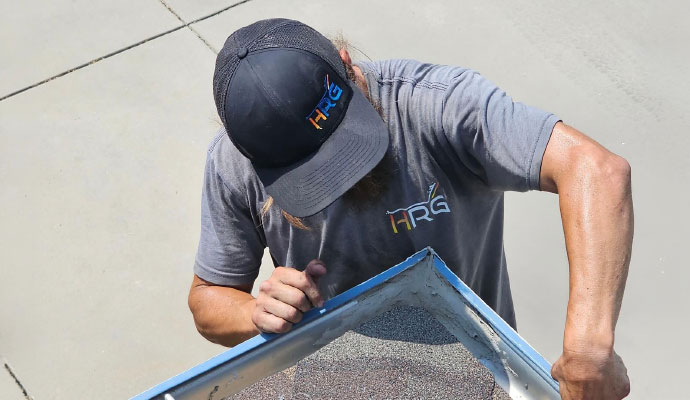 Worker repairing a gutter corner along the edge of a roof