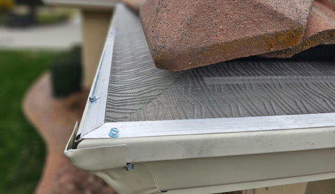 Close-up of a gutter guard screen installed under roof tiles