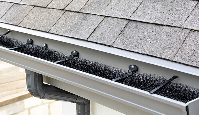 Bottle brush bristle gutter guard inserts fitted inside a residential aluminum rain gutter