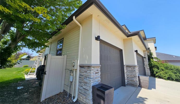 Improper downspout placement causing water pooling near a home foundation