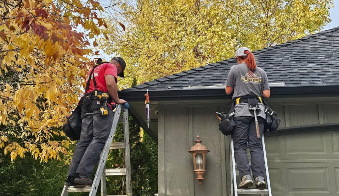 Professional team of Hunter Rain Gutters installing gutter on residential house roof