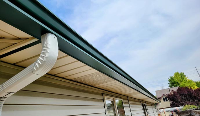 Properly installed gutter and downspout system along a residential roofline
