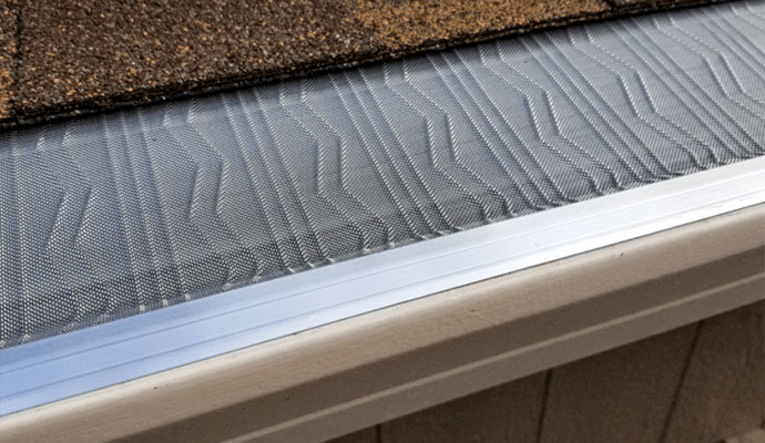 LeafBlaster Pro stainless steel micro-mesh gutter guard installed inside a gutter under roof shingles