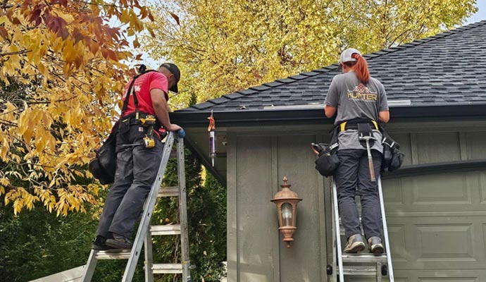 Gutter installation technicians working safely on ladders during installation