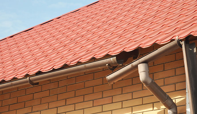 Broken and damaged gutter system attached to a brick wall