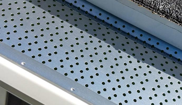 Close-up of a LeafRelief perforated metal gutter guard installed along the roof edge to allow water flow while blocking leaves and debris