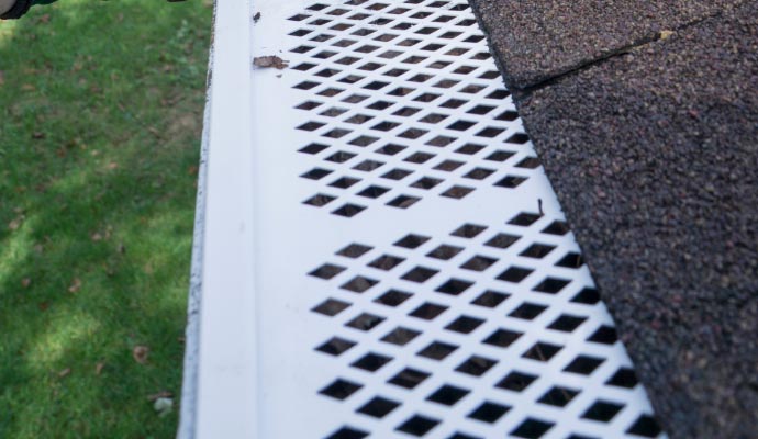 Perforated metal gutter guard installed along the roof edge, designed to block leaves and debris while allowing rainwater to flow into the gutter system