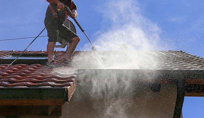 High-pressure power washing being used on a roof surface to remove dirt, buildup, and debris