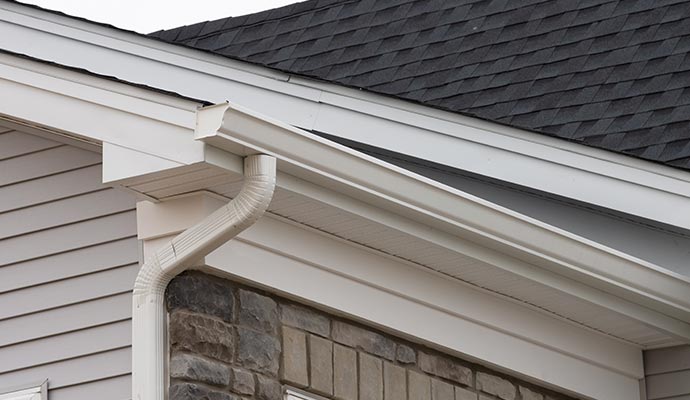 Rain gutter and downspout installed along a roof edge, directing rainwater away from the home to protect siding and foundation