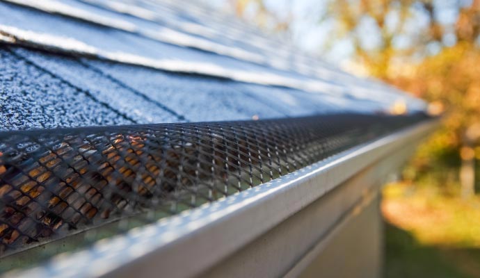 Reverse-curve gutter guard installed along the roof edge, designed to guide rainwater into the gutter while deflecting leaves and debris away