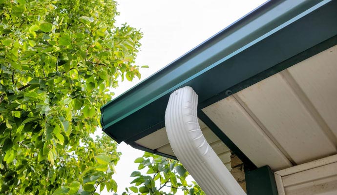 Specialty gutter installed along a roof edge with a curved downspout, designed to fit a unique roofline and manage rainwater effectively